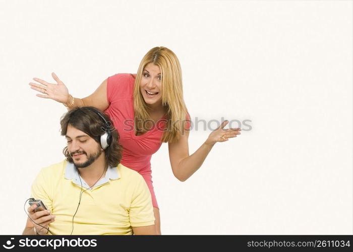 Mid adult man listening to music with a mature woman standing behind him and gesturing