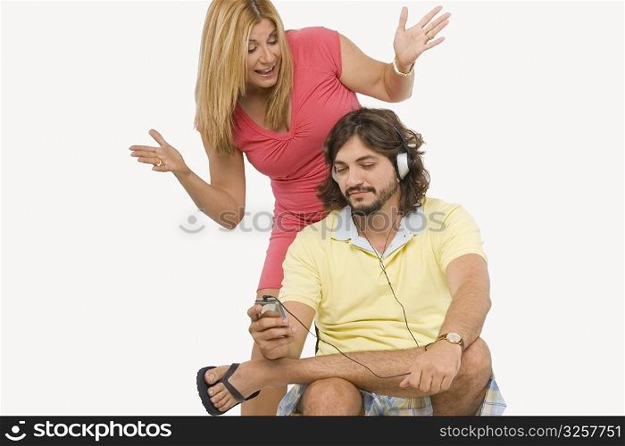 Mid adult man listening to music with a mature woman standing behind him and gesturing