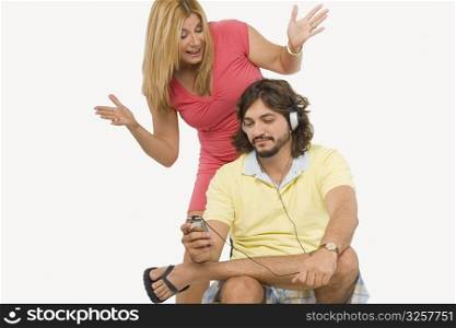 Mid adult man listening to music with a mature woman standing behind him and gesturing