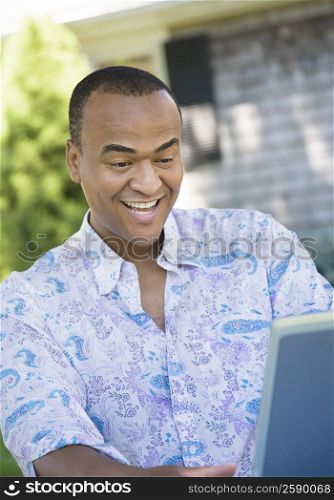 Mid adult man looking at a laptop and laughing