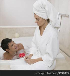 Mid adult man looking at a young woman sitting near him in the bathtub
