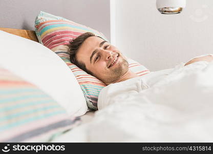 Mid adult man lying in bed under duvet