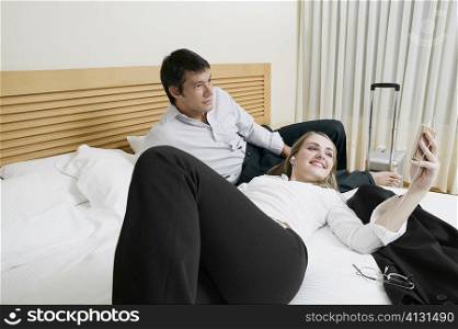 Mid adult man lying on the bed with a young woman listening to an MP3 player