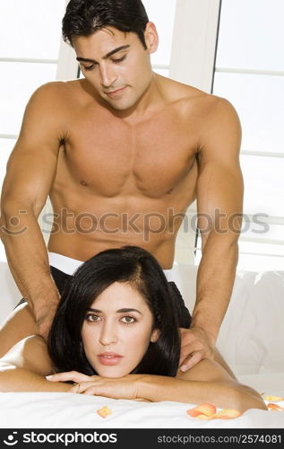 Mid adult man massaging a mid adult woman&acute;s shoulders on the bed