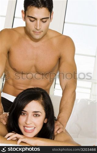 Mid adult man massaging a mid adult woman&acute;s shoulders on the bed