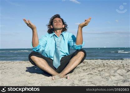 Mid adult man meditating on the beach
