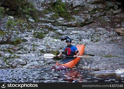 Mid adult man moving kayak from waters edge into river
