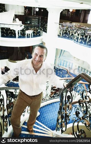 Mid adult man moving up on a staircase and smiling in a ship