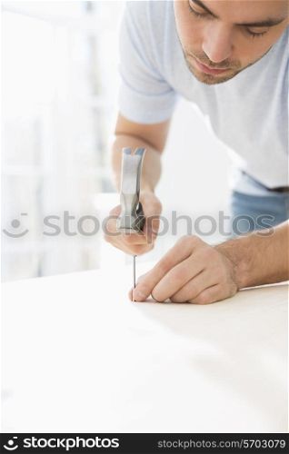 Mid-adult man nailing in table