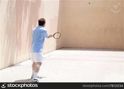 Mid adult man playing racquetball on a hot day.