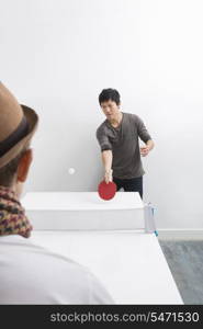 Mid adult man playing table tennis with friend