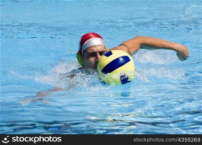 Mid adult man playing water polo in a swimming pool