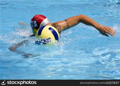 Mid adult man playing water polo in a swimming pool