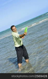 Mid adult man playing with a plastic disc on the beach