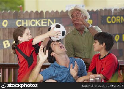 Mid adult man playing with his children and father in a restaurant