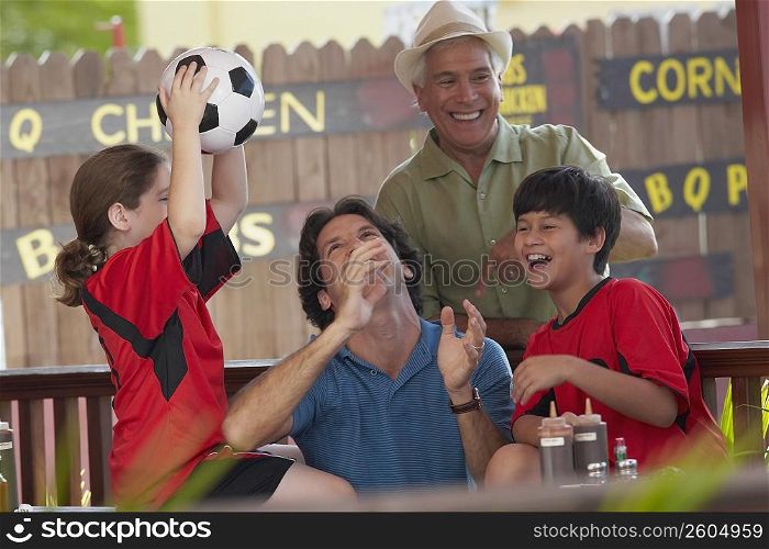 Mid adult man playing with his children in a restaurant and his father standing behind him
