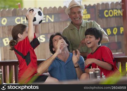 Mid adult man playing with his children in a restaurant and his father standing behind him
