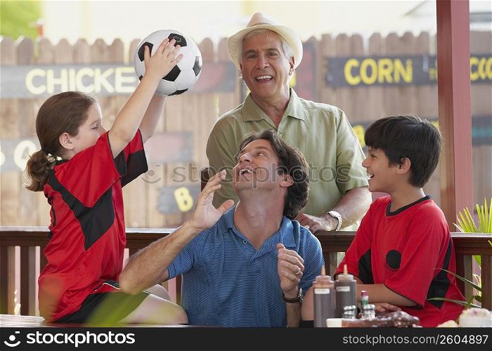 Mid adult man playing with his children in a restaurant with his father standing behind him
