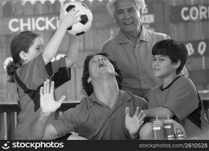 Mid adult man playing with his children in a restaurant with his father standing behind him