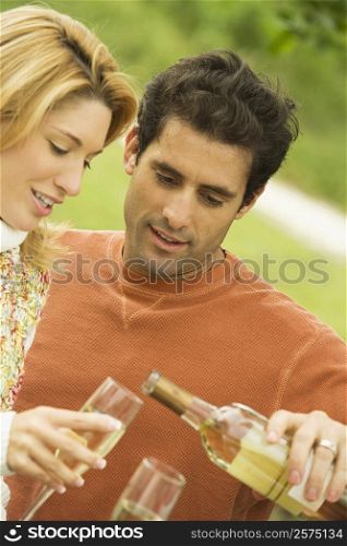 Mid adult man pouring champagne into a champagne flute