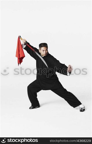 Mid adult man practicing martial arts with a sword