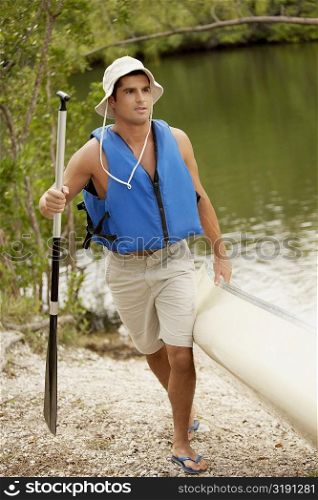 Mid adult man pulling a canoe