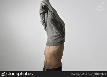 Mid-adult man pulling sweater over head
