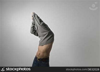 Mid-adult man pulling sweater over head