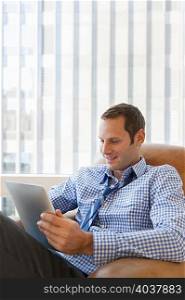 Mid adult man relaxing at home with digital tablet