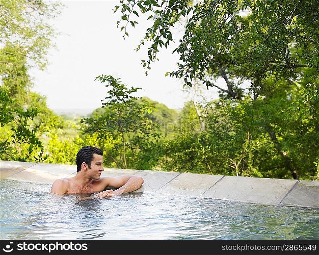 Mid adult man sitting in pool looking at view