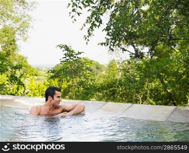 Mid adult man sitting in pool looking at view
