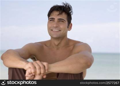Mid adult man sitting on the beach and smiling