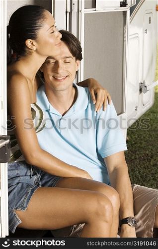Mid adult man sitting with his arm around a young woman