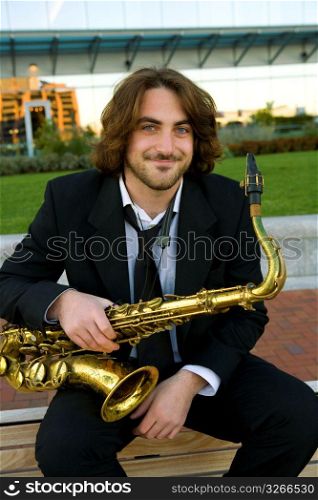 Mid adult man sitting with saxophone, portrait