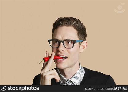 Mid adult man smoking red chili pepper over colored background