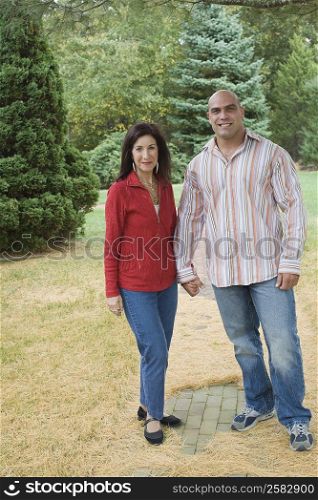 Mid adult man standing with a mature woman in a lawn and smiling