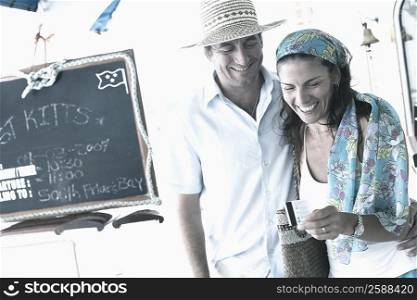 Mid adult man standing with a mid adult woman holding a credit card and smiling