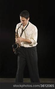 Mid adult man stands in shirt playing the saxophone