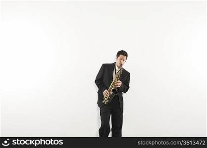 Mid adult man stands in suit playing the saxophone