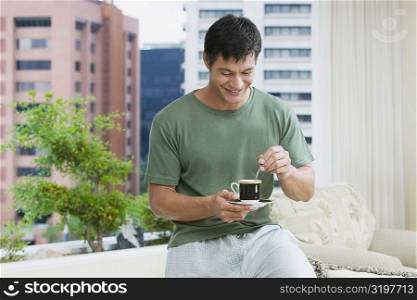 Mid adult man stirring tea with a teaspoon