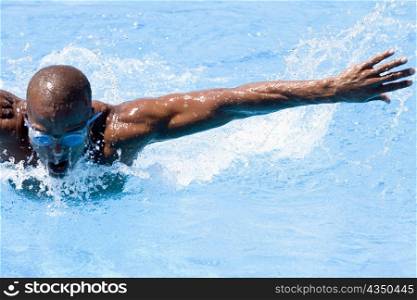 Mid adult man swimming the butterfly stroke in a swimming pool