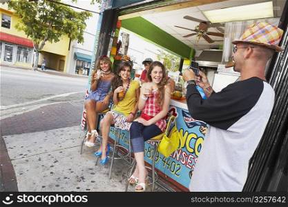 Mid adult man taking a photograph of a teenage girl and her three friends