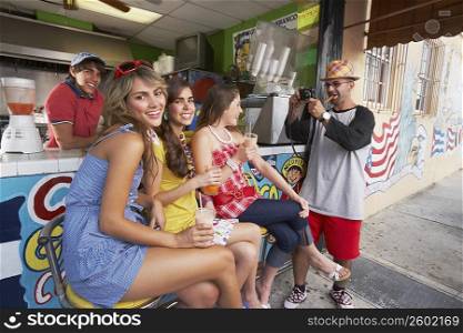 Mid adult man taking a photograph of a teenage girl and her two friends