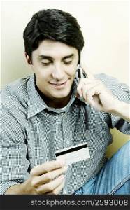 Mid adult man talking on a mobile phone and holding a credit card
