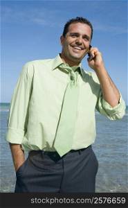 Mid adult man talking on a mobile phone on the beach