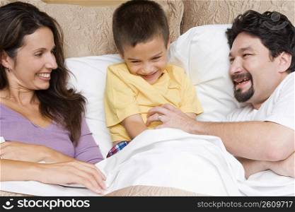 Mid adult man tickling his son with a mid adult woman looking at them