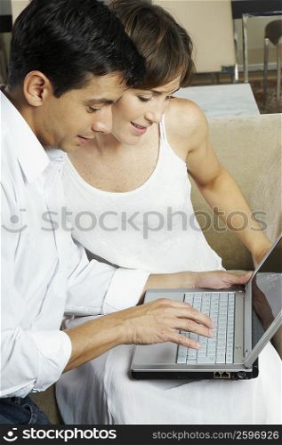 Mid adult man using a laptop with a young woman beside him
