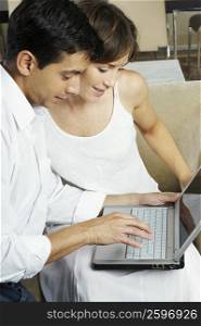 Mid adult man using a laptop with a young woman beside him