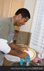 Mid-adult man washing dishes, smiling