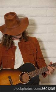 Mid adult man wearing cowboy hat and playing guitar